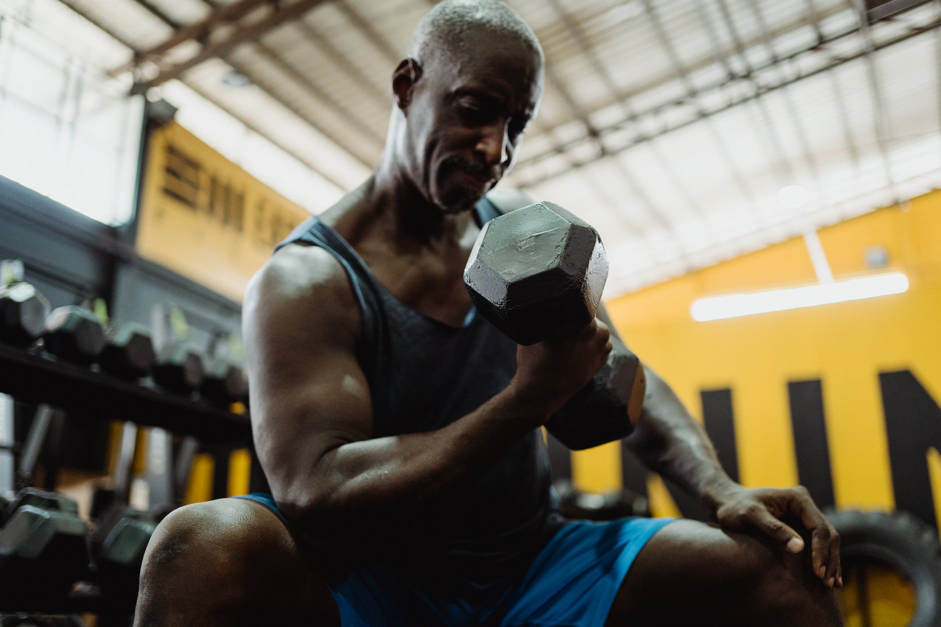 man in blue tank top holding black dumbbell