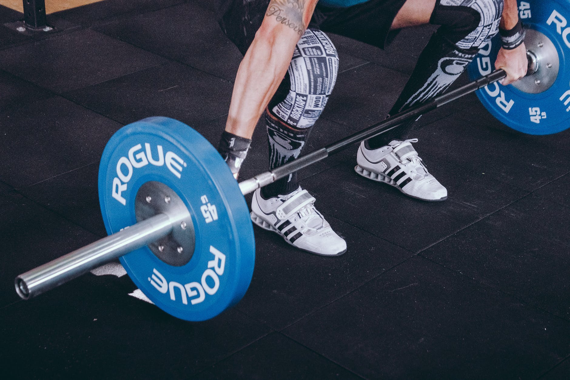 man with lift stance holds blue rogue adjustable barbell