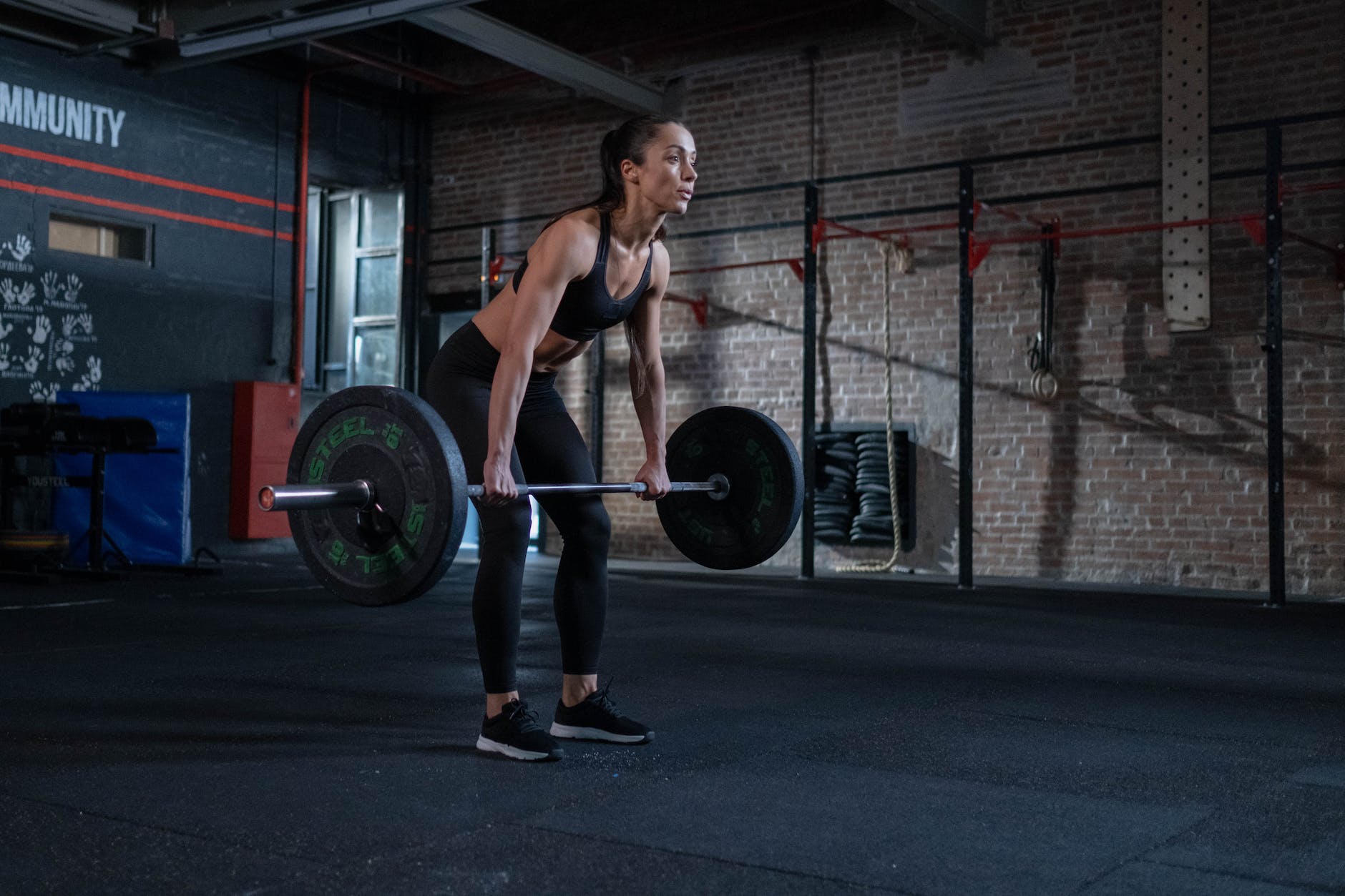 woman in black sportswear lifting a barbell